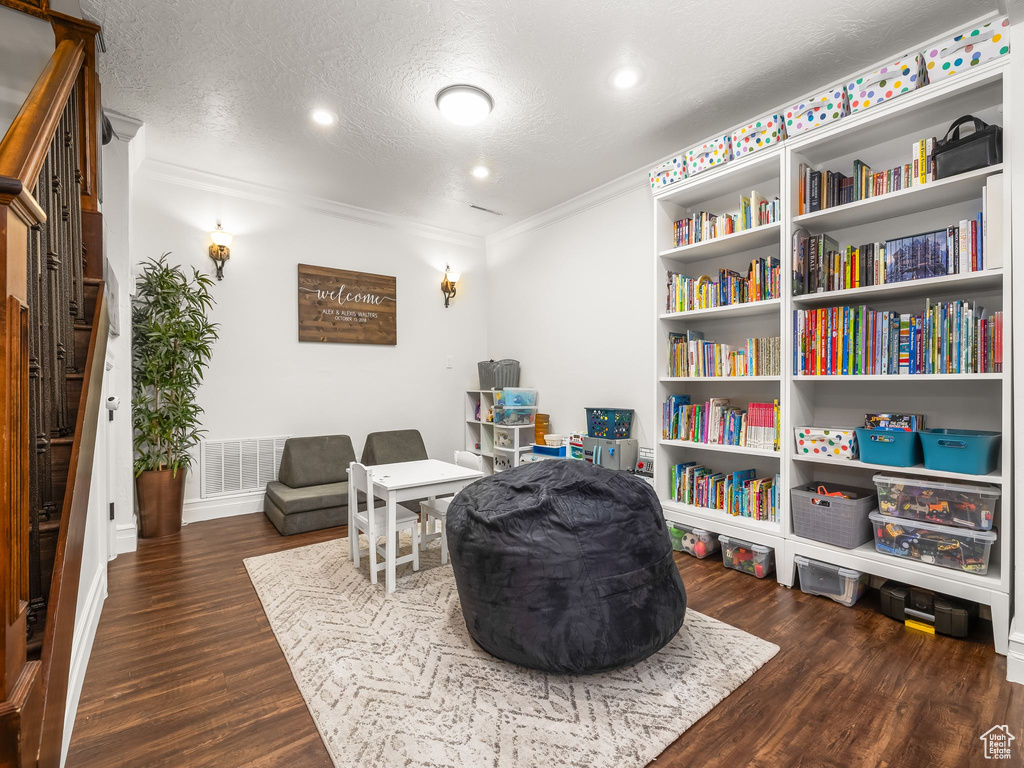 Sitting room featuring wood finished floors, ornamental molding, stairway, a textured ceiling, and recessed lighting