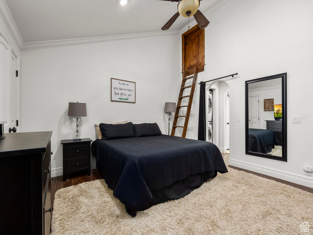 Bedroom featuring crown molding, arched walkways, dark wood-type flooring, and ceiling fan