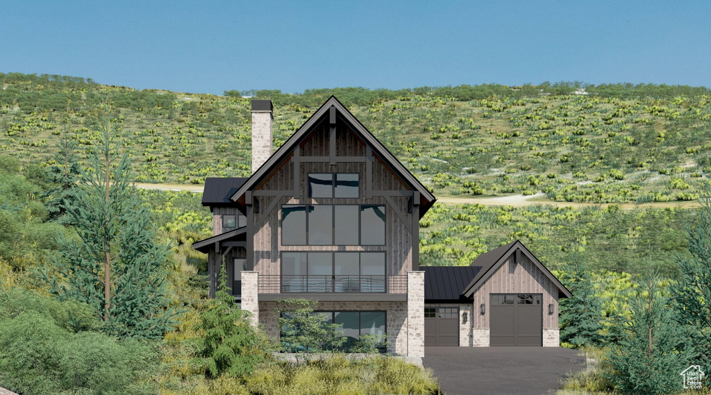 View of front of house with a chimney, a balcony, a standing seam roof, a metal roof, and asphalt driveway