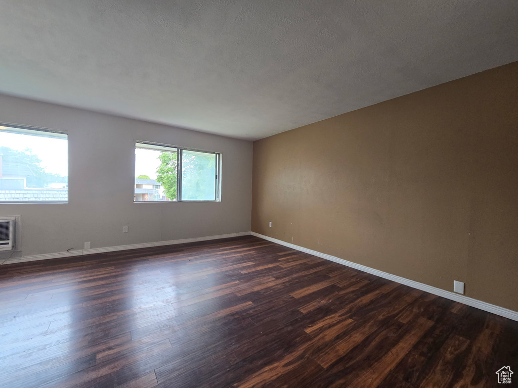 Spare room featuring dark wood-type flooring and baseboards
