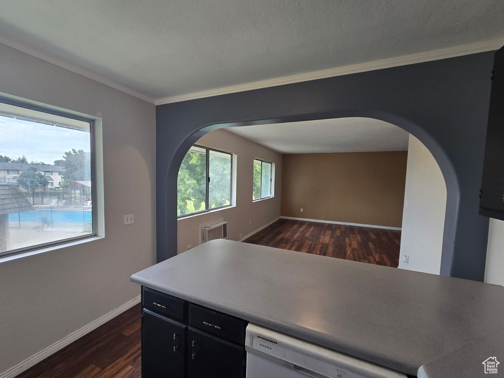 Kitchen featuring arched walkways, dishwasher, dark wood-style floors, and ornamental molding