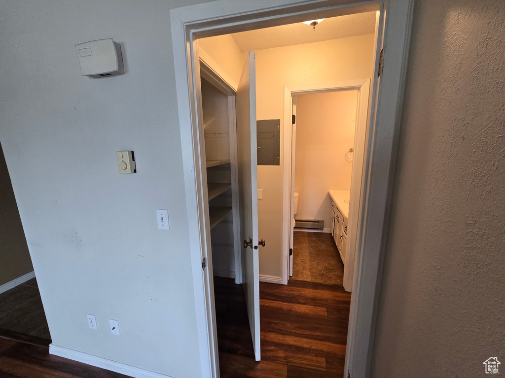 Hallway featuring dark wood-style flooring, baseboard heating, and electric panel