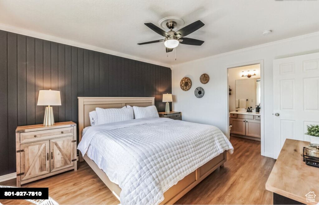Bedroom featuring light wood-style floors, crown molding, ensuite bath, and a ceiling fan