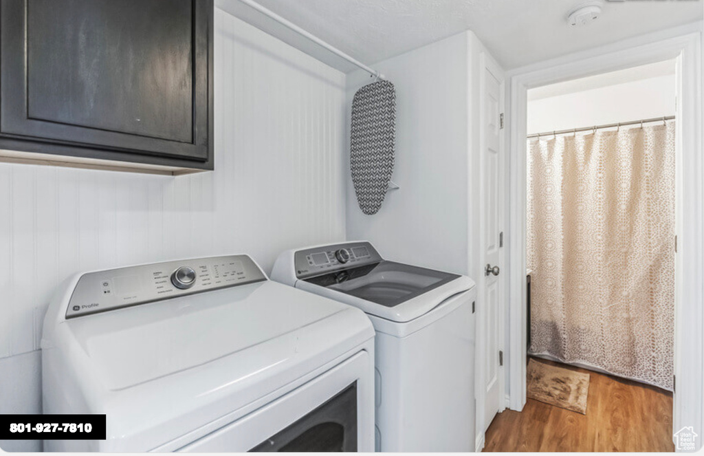 Laundry room with washer and dryer, light wood-style flooring, and cabinet space