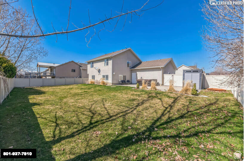 Rear view of house with stucco siding, a fenced backyard, and a garage