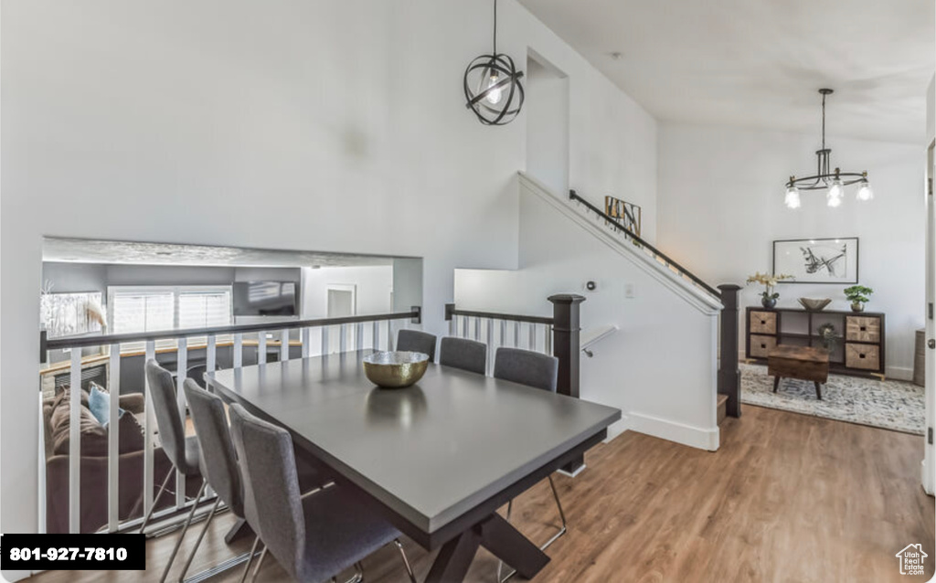 Dining room featuring wood finished floors, a chandelier, and a towering ceiling