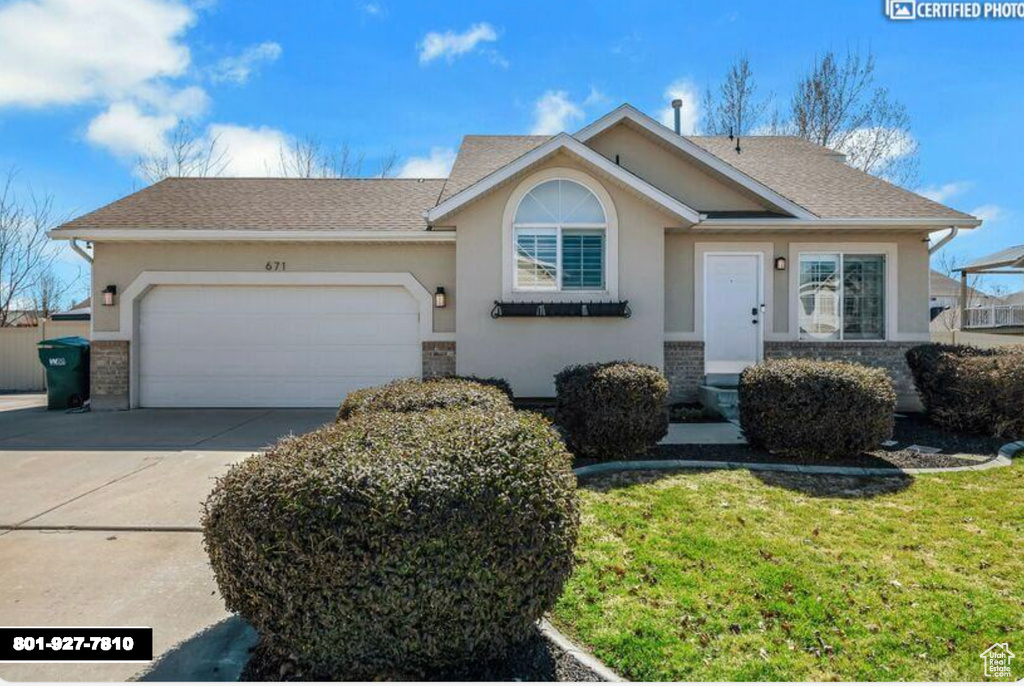 Ranch-style home with a garage, driveway, stucco siding, and brick siding