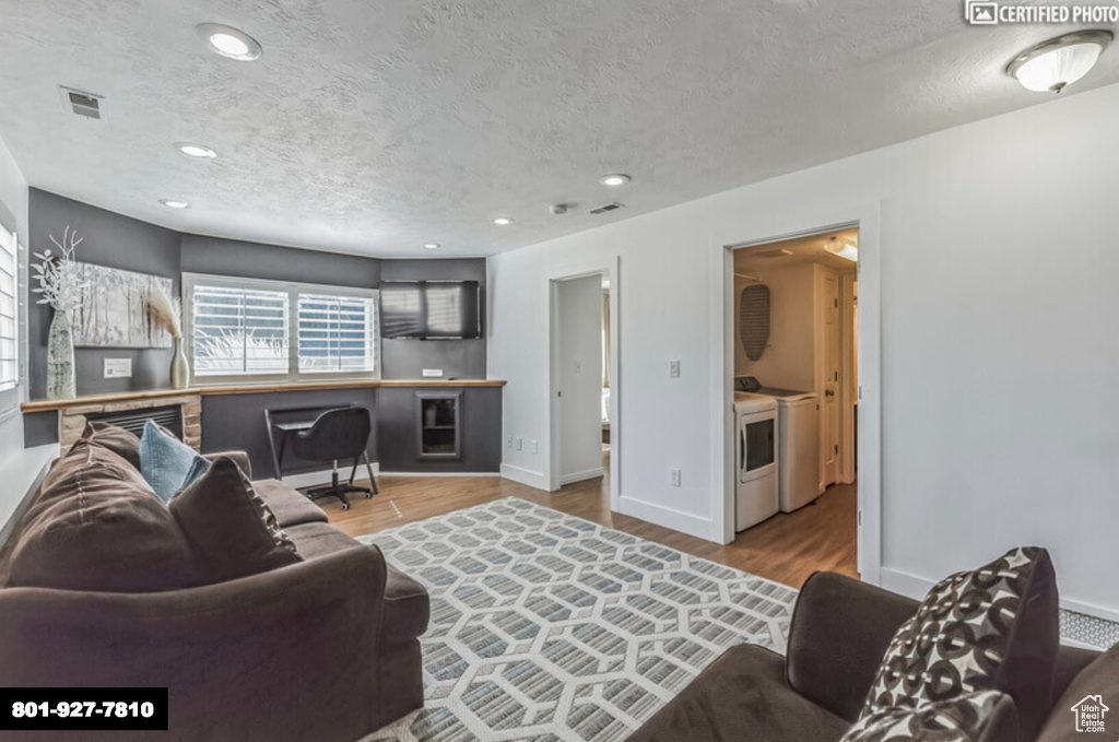 Living area with washer and clothes dryer, wood finished floors, a textured ceiling, and recessed lighting