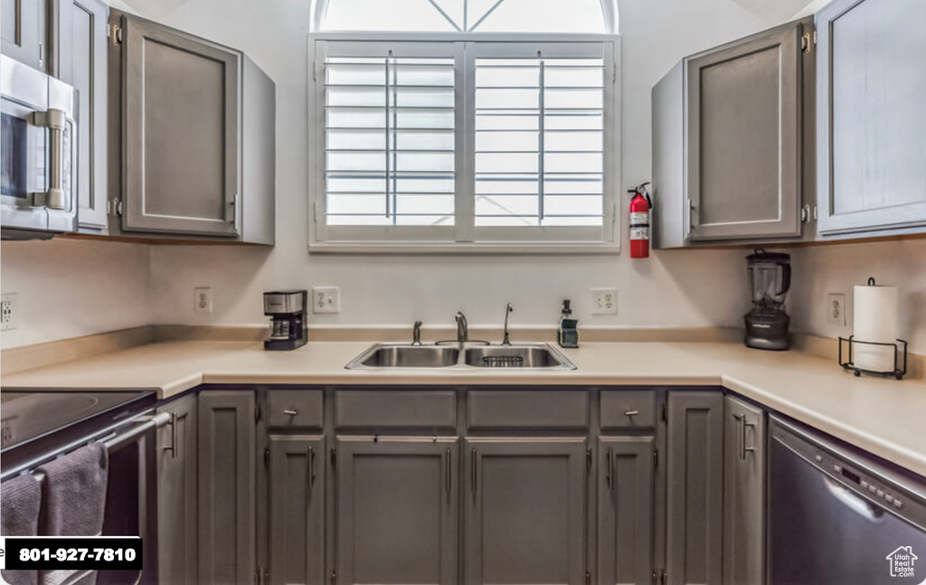 Kitchen featuring stainless steel appliances, gray cabinets, and light countertops