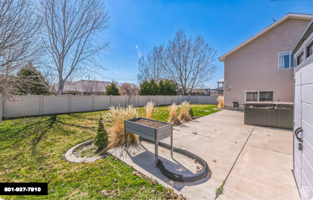 Fenced backyard featuring a hot tub and a patio area