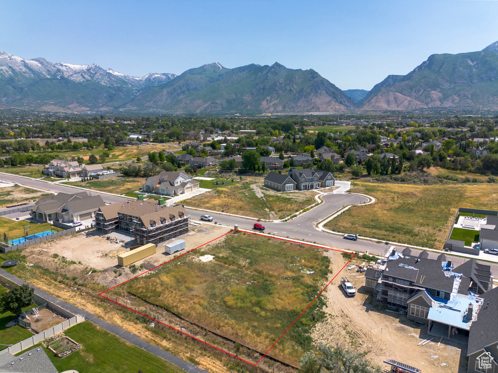 Aerial view of residential area with property boundaries highlighted and a mountain backdrop