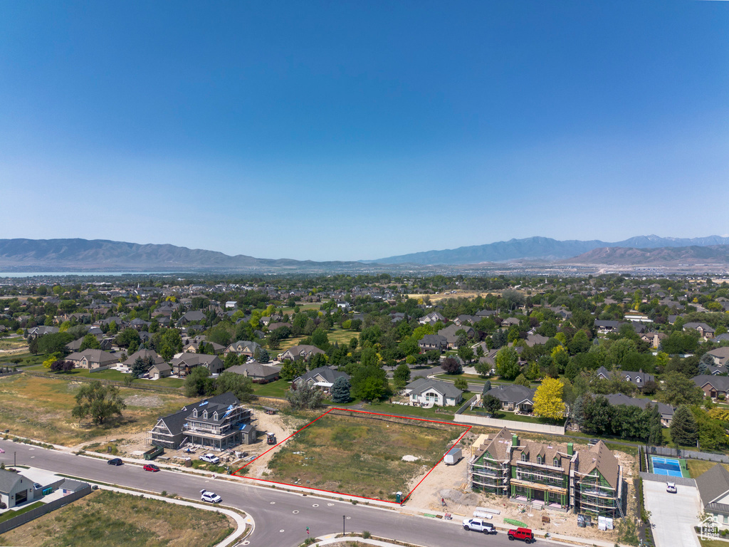 Aerial view of residential area with property boundaries highlighted and a mountainous background