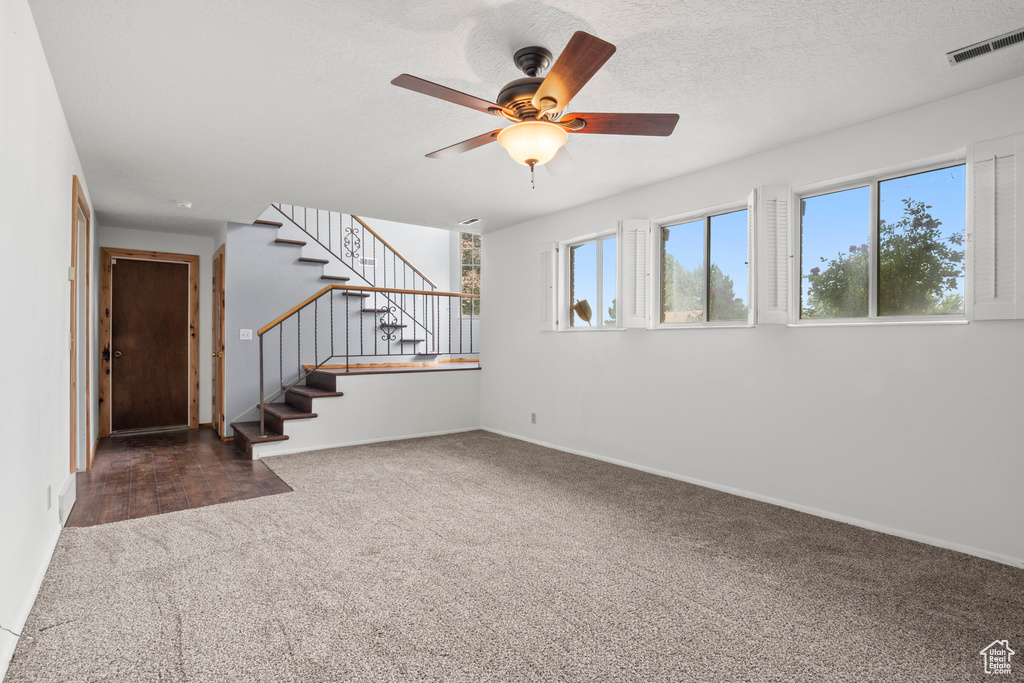 Unfurnished room featuring carpet floors, stairway, and a ceiling fan