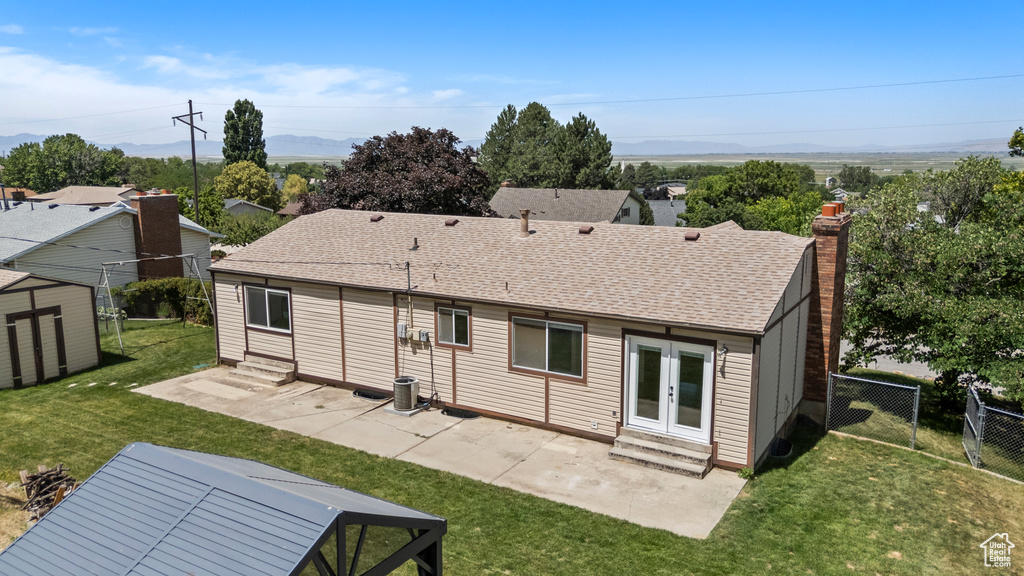 Back of property with entry steps, a patio, a chimney, and french doors