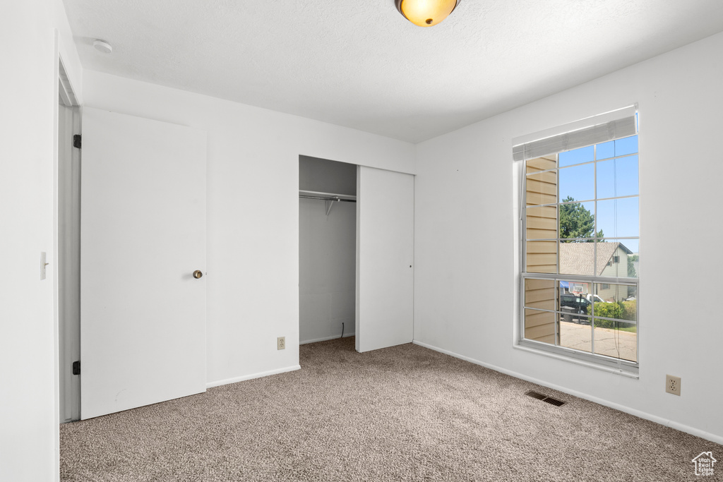 Unfurnished bedroom featuring carpet flooring and a closet
