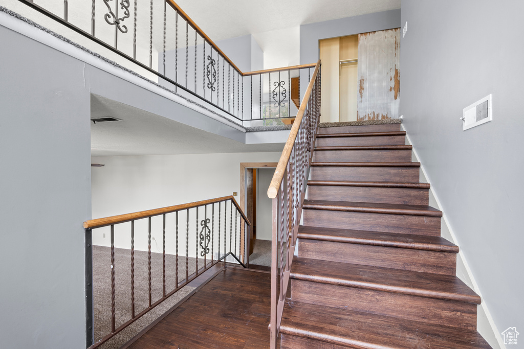 Stairs with wood finished floors and a high ceiling