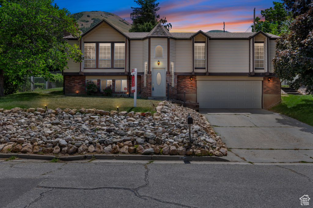 Split foyer home featuring an attached garage, brick siding, and concrete driveway
