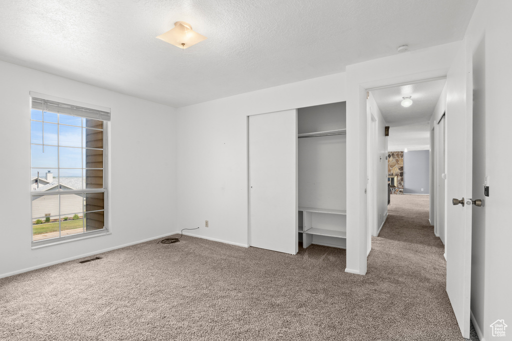 Unfurnished bedroom with carpet flooring, a closet, and a textured ceiling