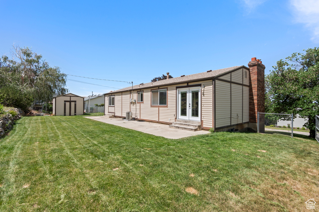Back of property with french doors, a storage shed, a patio, a chimney, and entry steps