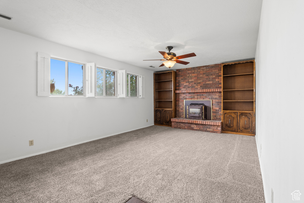 Unfurnished living room featuring ceiling fan, carpet, a fireplace, and built in features