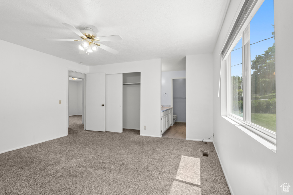 Unfurnished bedroom featuring light carpet, connected bathroom, a closet, and ceiling fan