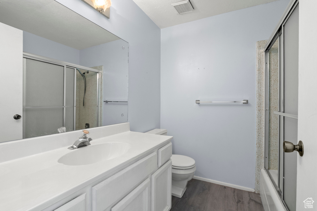 Bathroom with vanity, wood finished floors, and enclosed tub / shower combo