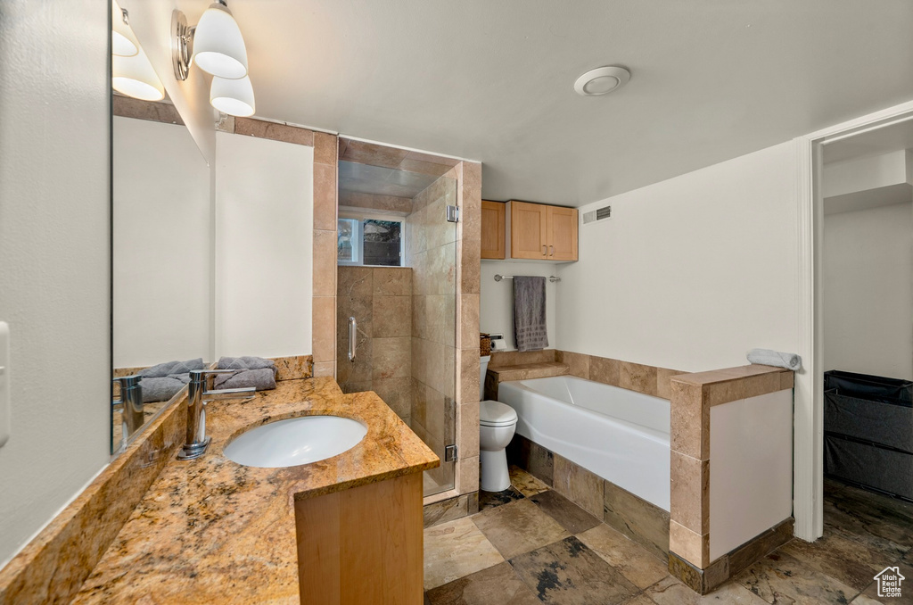 Full bath with a bath, vanity, a stall shower, and stone finish flooring