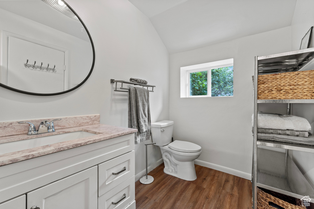 Bathroom with wood finished floors, lofted ceiling, and vanity