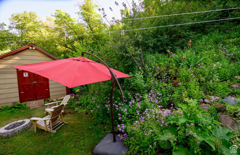 View of yard with an outdoor fire pit and a storage shed