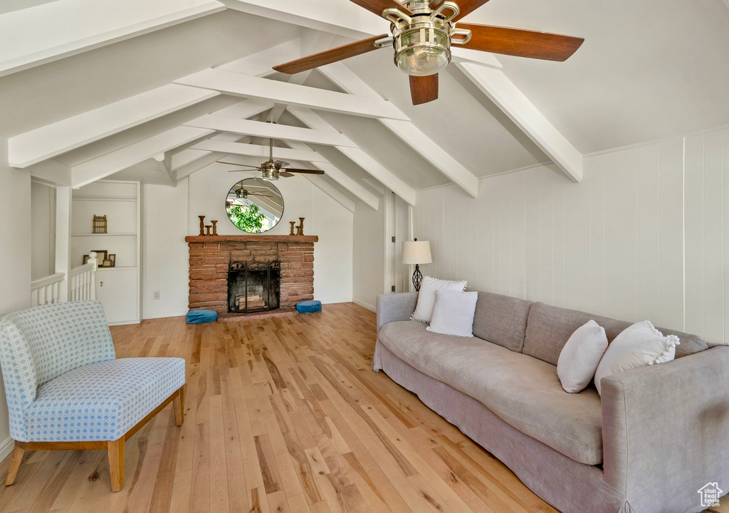 Living room with a ceiling fan, light wood-style floors, and a fireplace