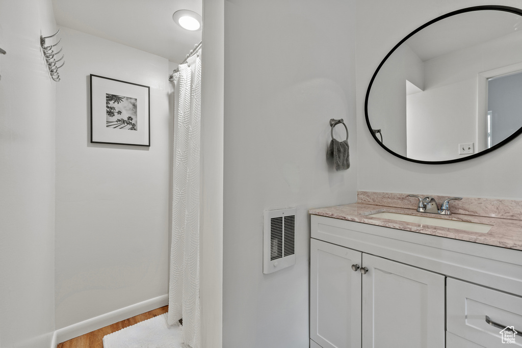 Full bathroom featuring wood finished floors, vanity, and curtained shower
