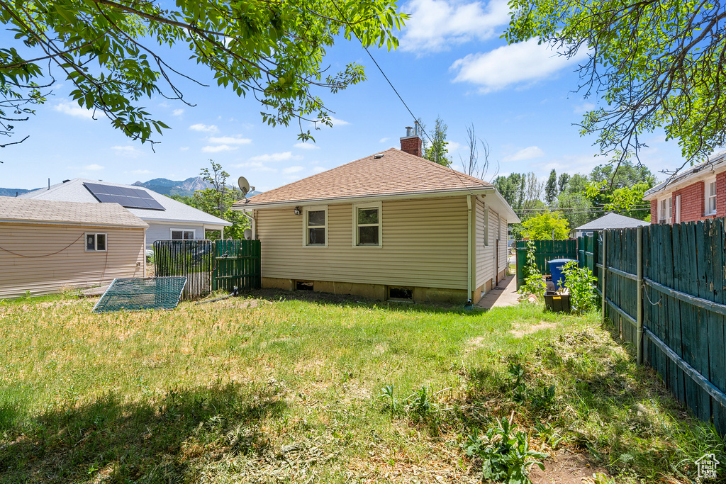 Rear view of house with a fenced backyard, a chimney, and a mountain view