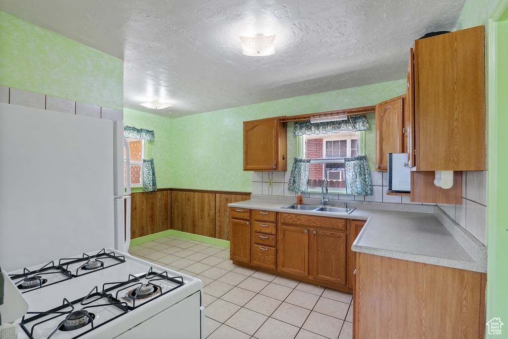 Kitchen with white appliances, healthy amount of natural light, light countertops, wood walls, and wainscoting