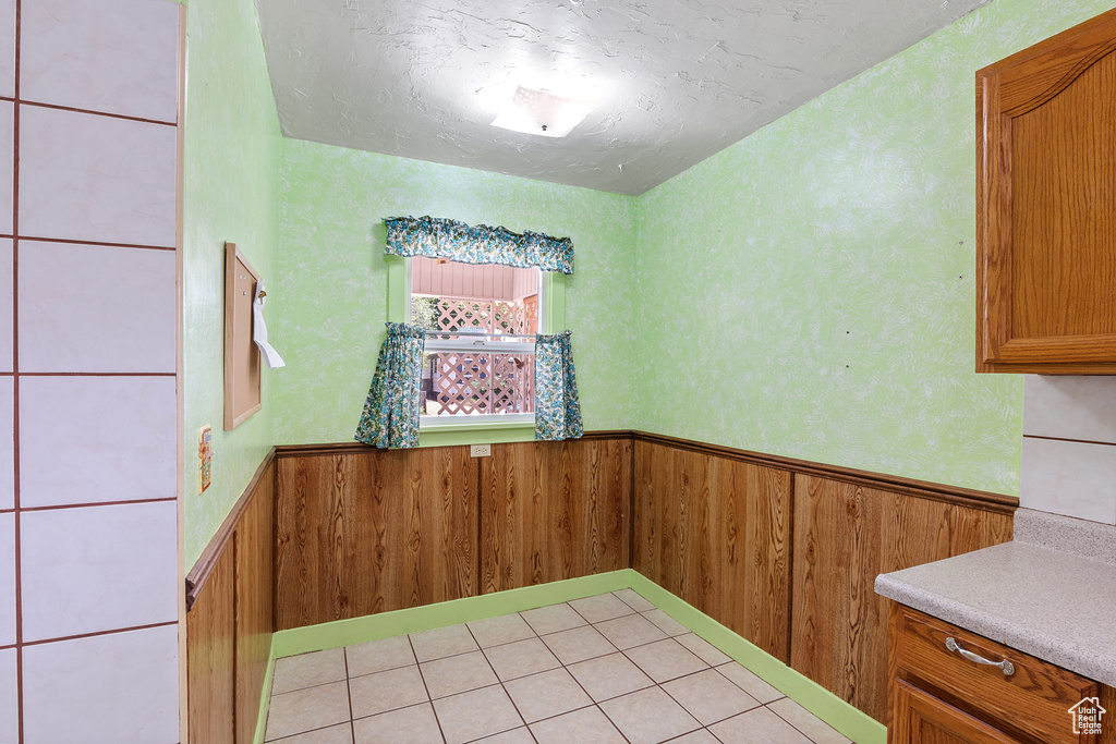 Unfurnished dining area with a wainscoted wall, wooden walls, and a textured ceiling