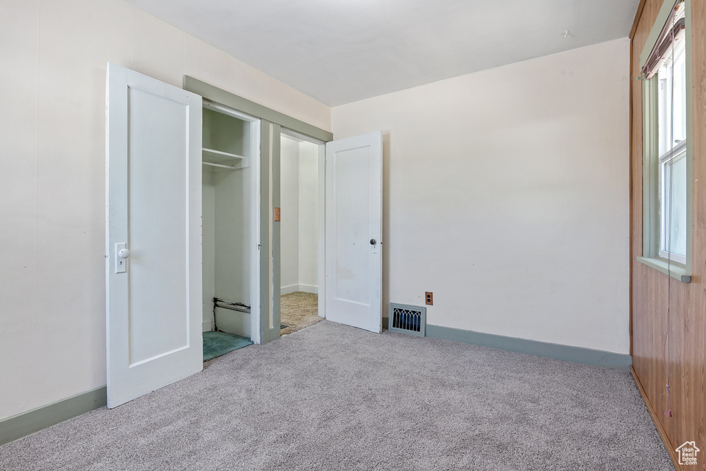 Unfurnished bedroom with carpet floors, multiple windows, and a closet