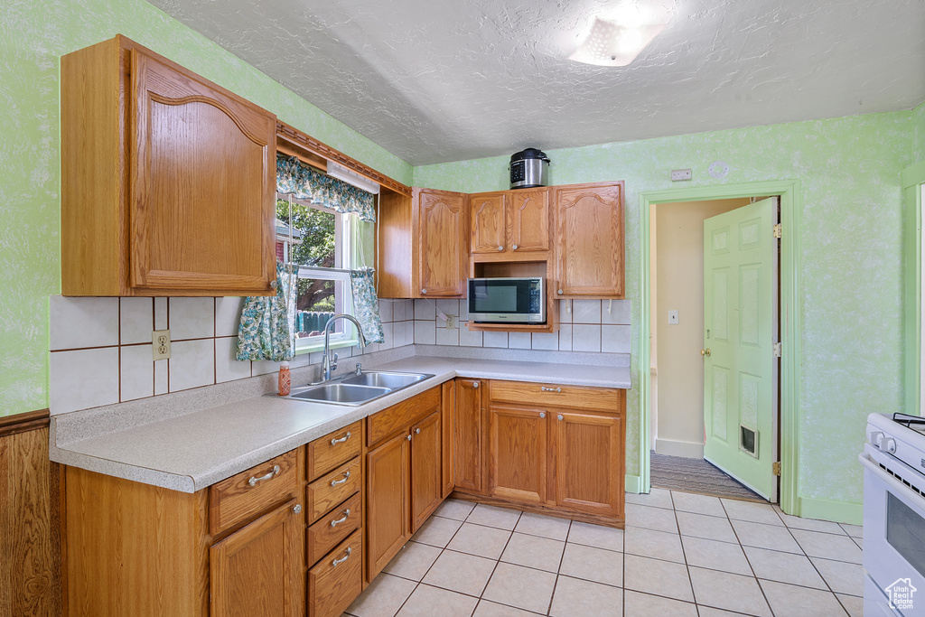 Kitchen with stainless steel microwave, white gas stove, light countertops, tasteful backsplash, and a textured ceiling