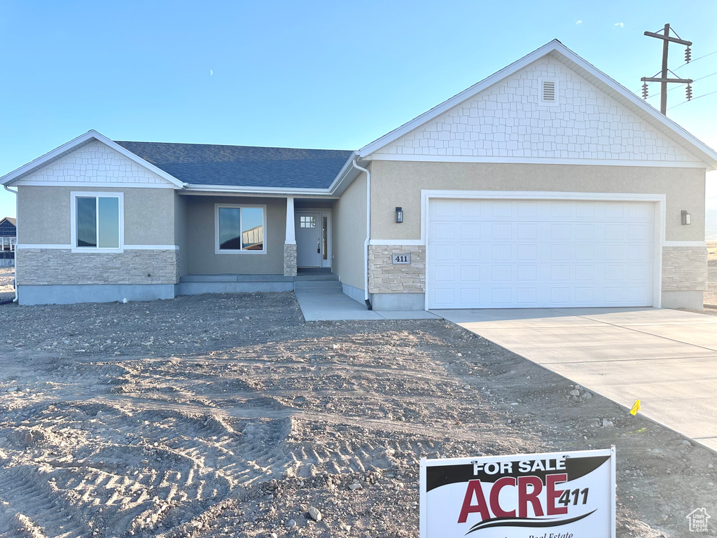 Ranch-style house with stone siding, stucco siding, concrete driveway, and a garage