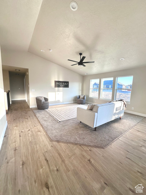 Living room with vaulted ceiling, wood finished floors, a textured ceiling, a ceiling fan, and recessed lighting