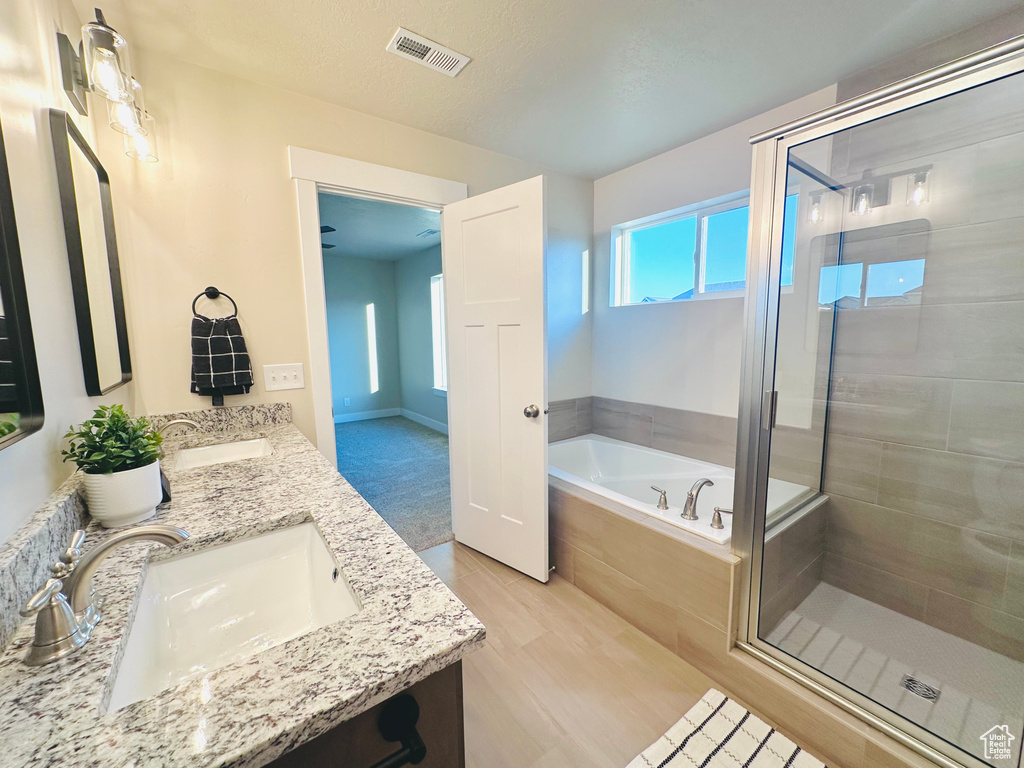 Full bathroom with a stall shower, a bath, double vanity, and wood finished floors