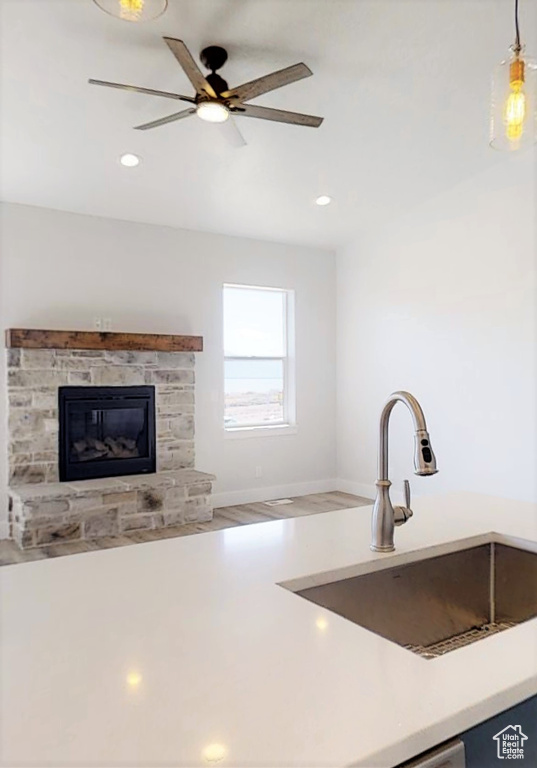 Kitchen featuring decorative light fixtures, ceiling fan, recessed lighting, light countertops, and a fireplace