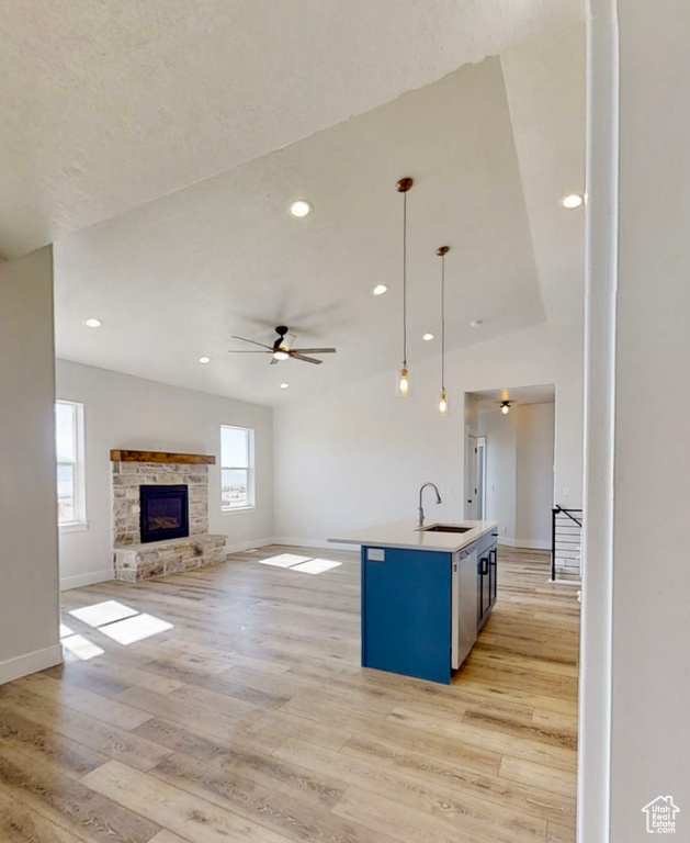 Kitchen with light wood-style flooring, a ceiling fan, open floor plan, a kitchen island with sink, and decorative light fixtures