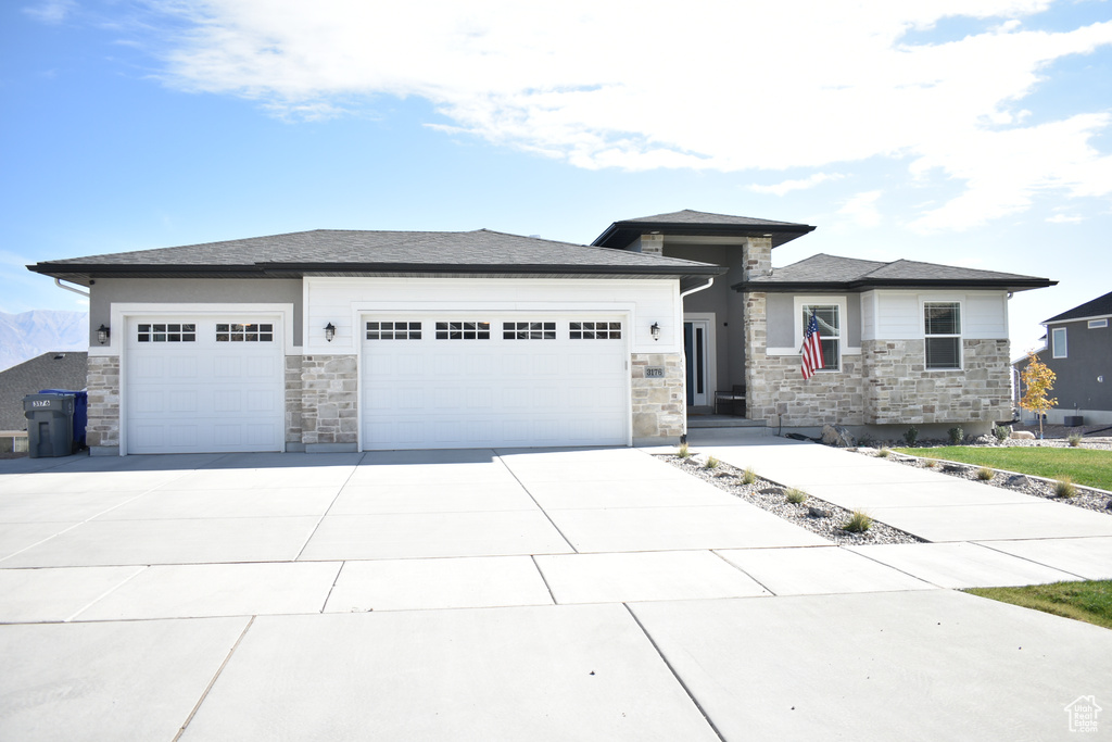 Prairie-style home with stone siding, a garage, and concrete driveway