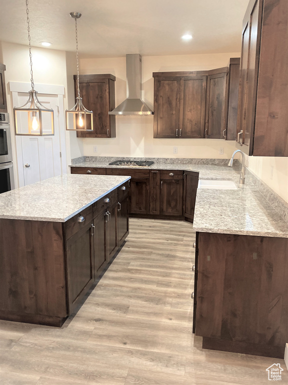 Kitchen with wall chimney exhaust hood, light wood-style flooring, dark brown cabinetry, and recessed lighting