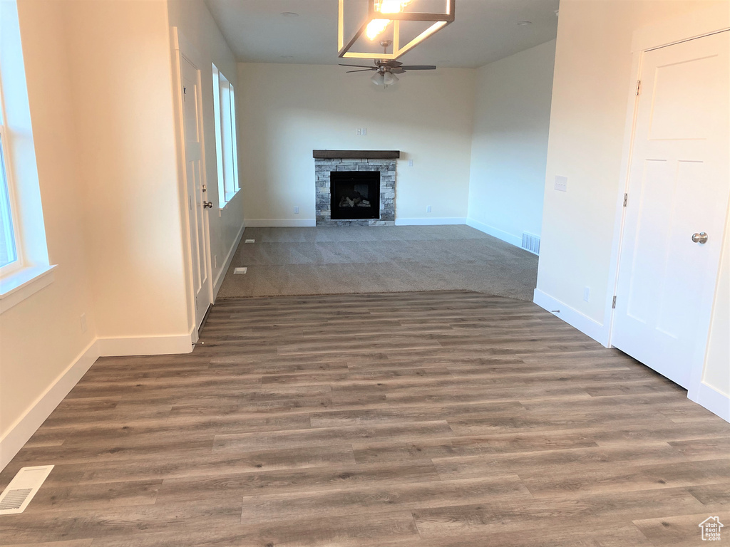 Unfurnished living room featuring a ceiling fan, a fireplace, and wood finished floors