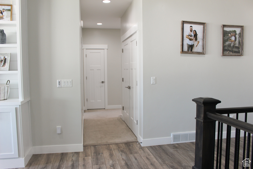 Hall with wood finished floors and recessed lighting