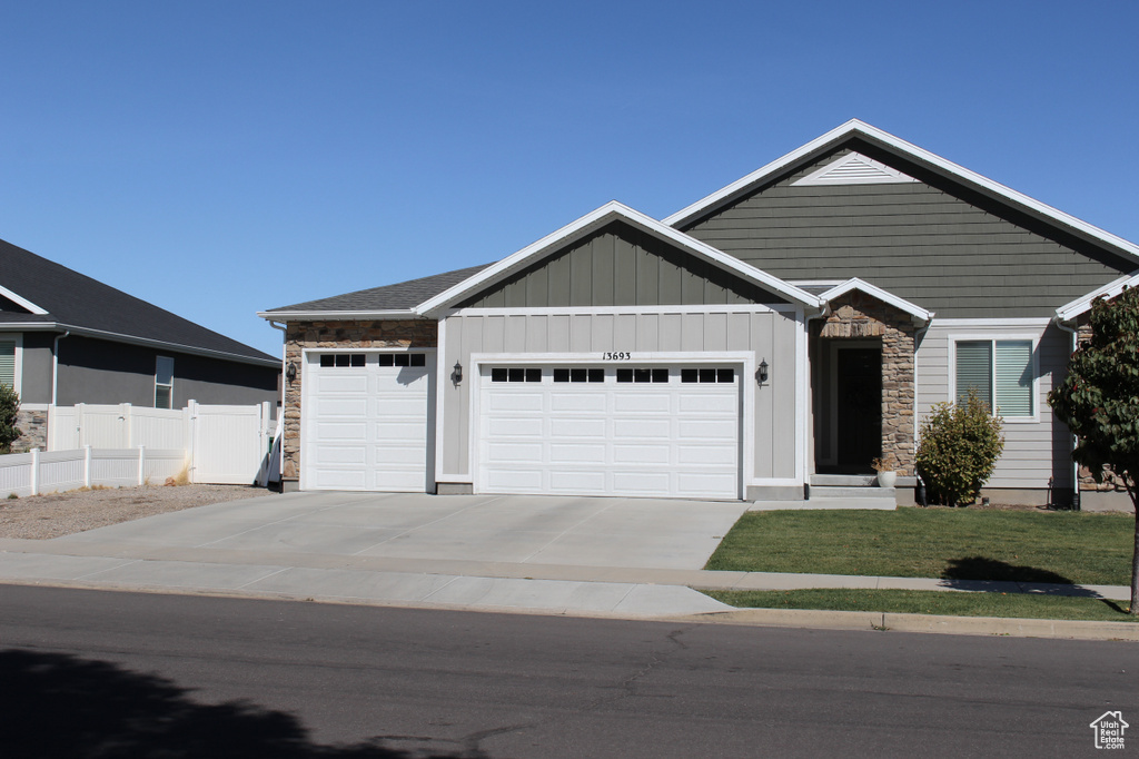 View of front of property featuring a garage, stone siding, concrete driveway, and board and batten siding