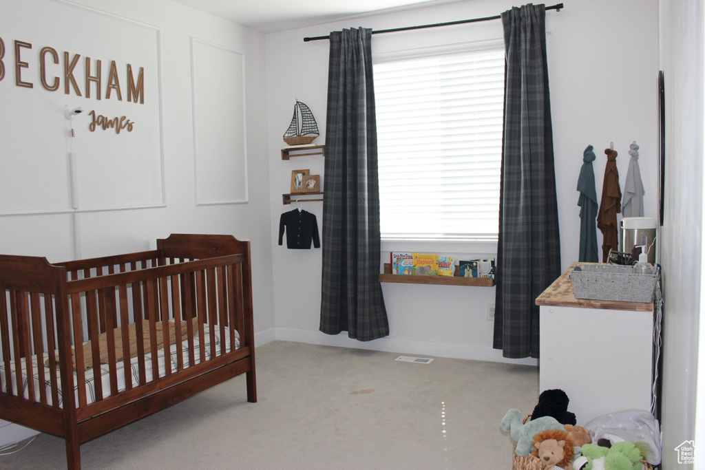 Bedroom with a crib and carpet flooring