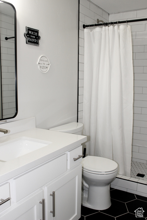 Full bath with vanity, tiled shower, and tile patterned floors