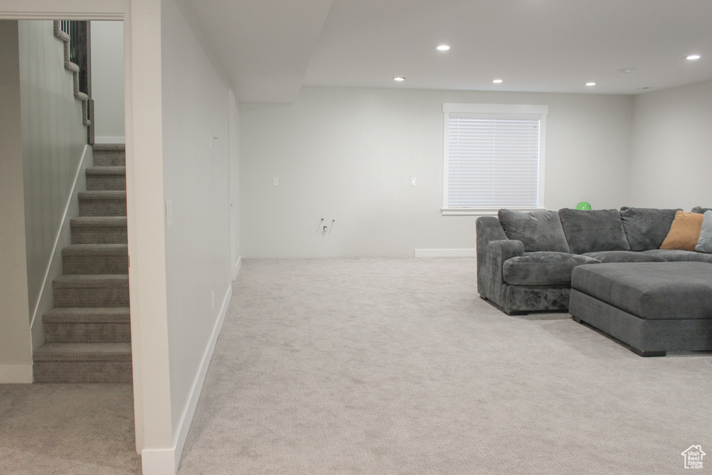 Carpeted living room with recessed lighting and stairway