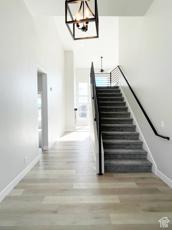 Stairs with a chandelier, wood finished floors, and a high ceiling
